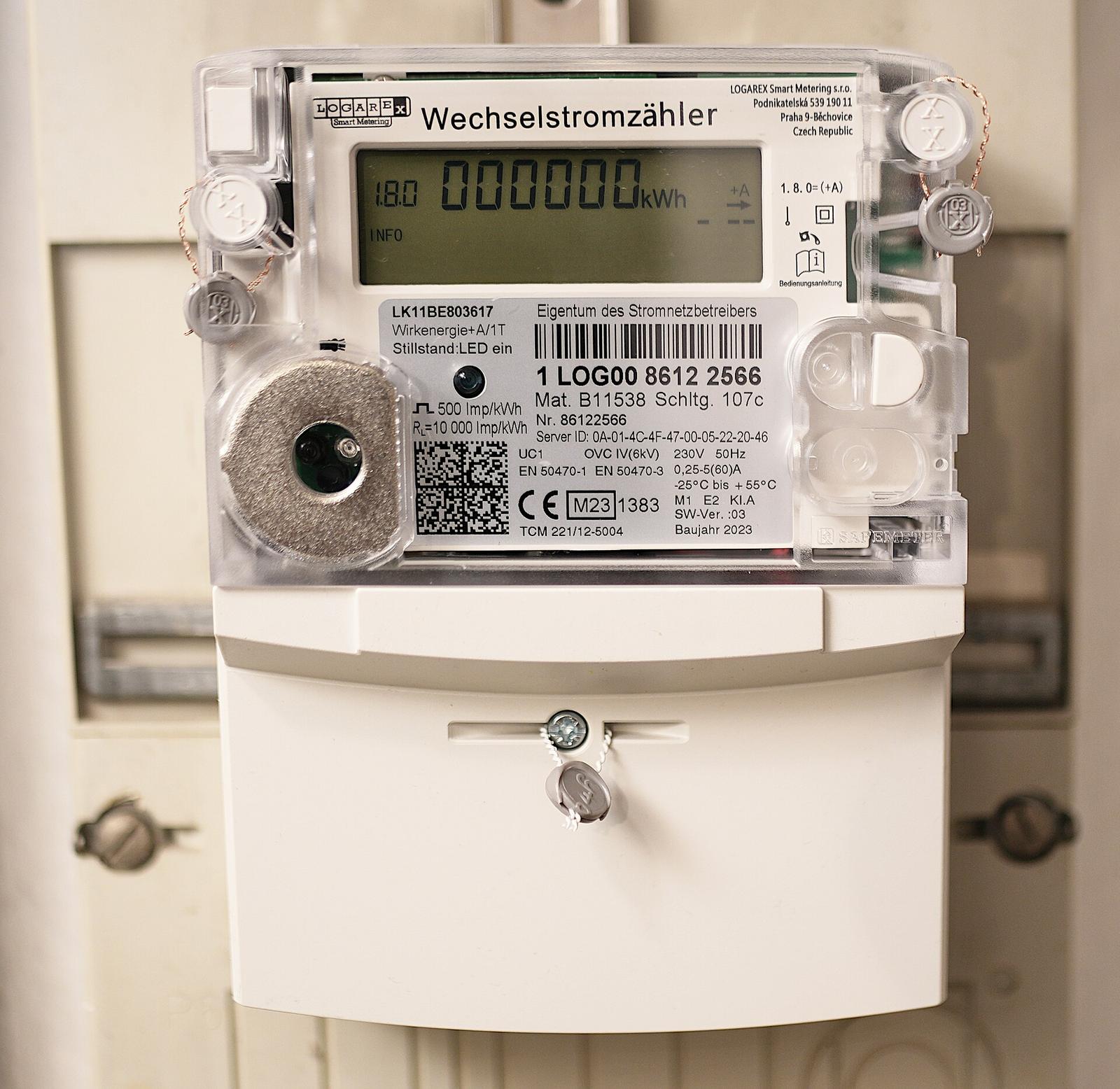 Nieuwe digitale elektriciteitsmeter met lcd-scherm dat 000000 kWh aangeeft, gemonteerd in een witte meterkast